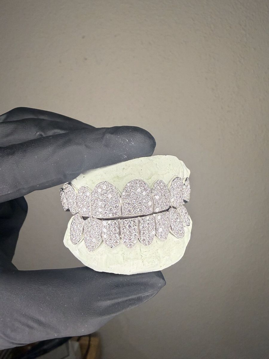 Silver honeycomb grill set with moissanite, held in a black glove